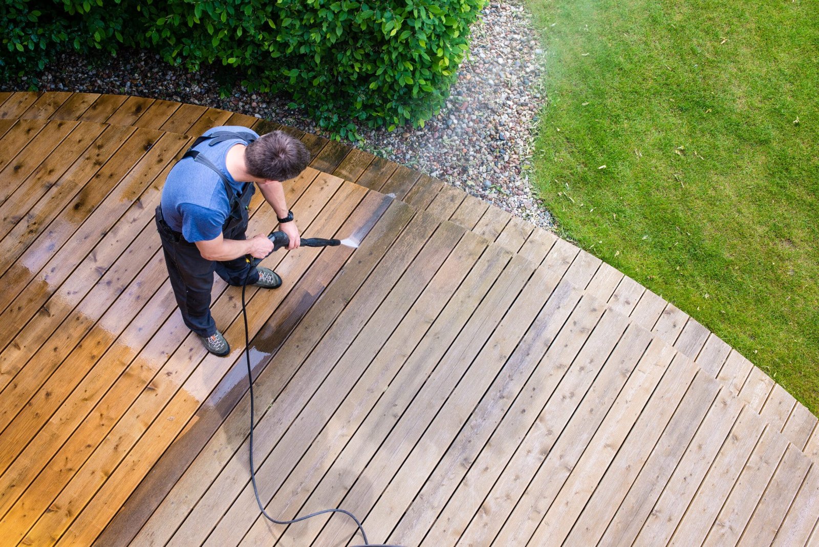 man cleaning terrace with a power washer high water pressure cleaner on wooden terrace surface